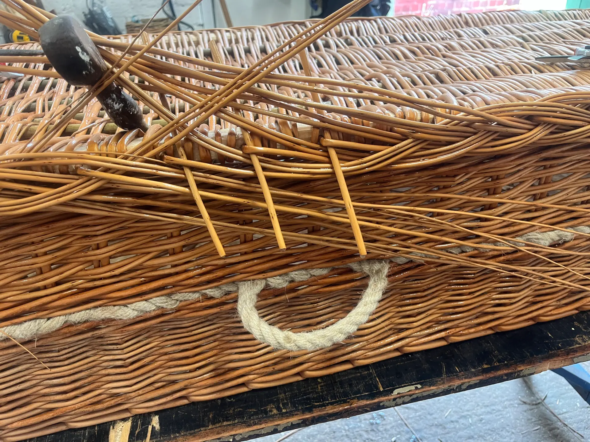 Buff willow rods being woven into a coffin by hand